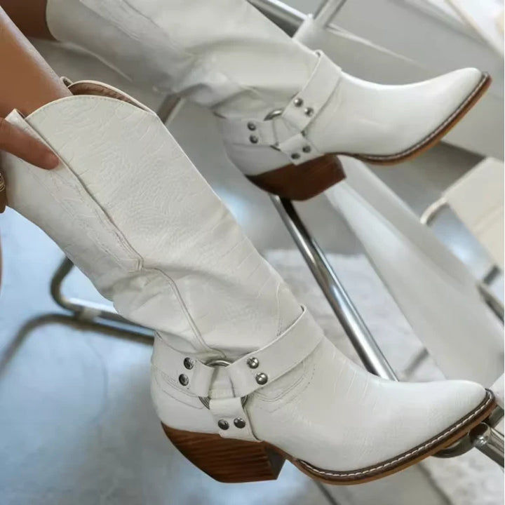 Side angle of women's knee-high cow print boots with Western-inspired buckle straps