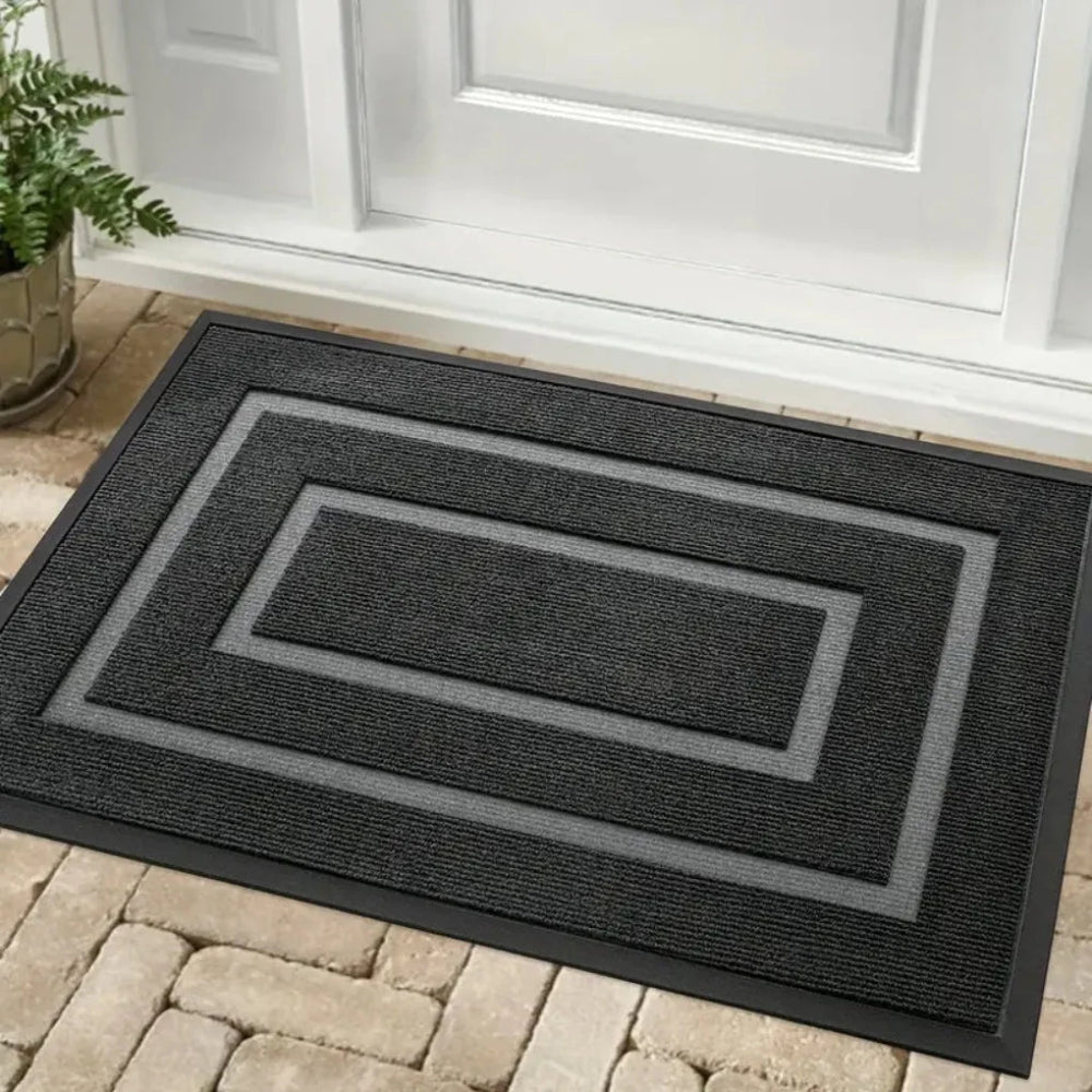 Gumowa mata wejściowa z geometrycznym wzorem w kolorze czarnym na tarasie przed drzwiami