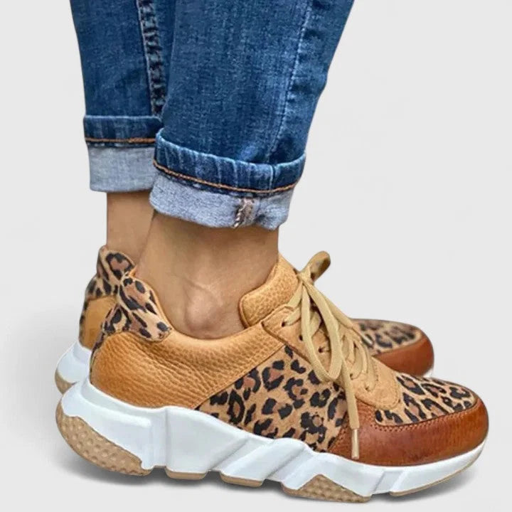 Women's leopard print trainers with chunky white sole and tan leather accents on model's feet