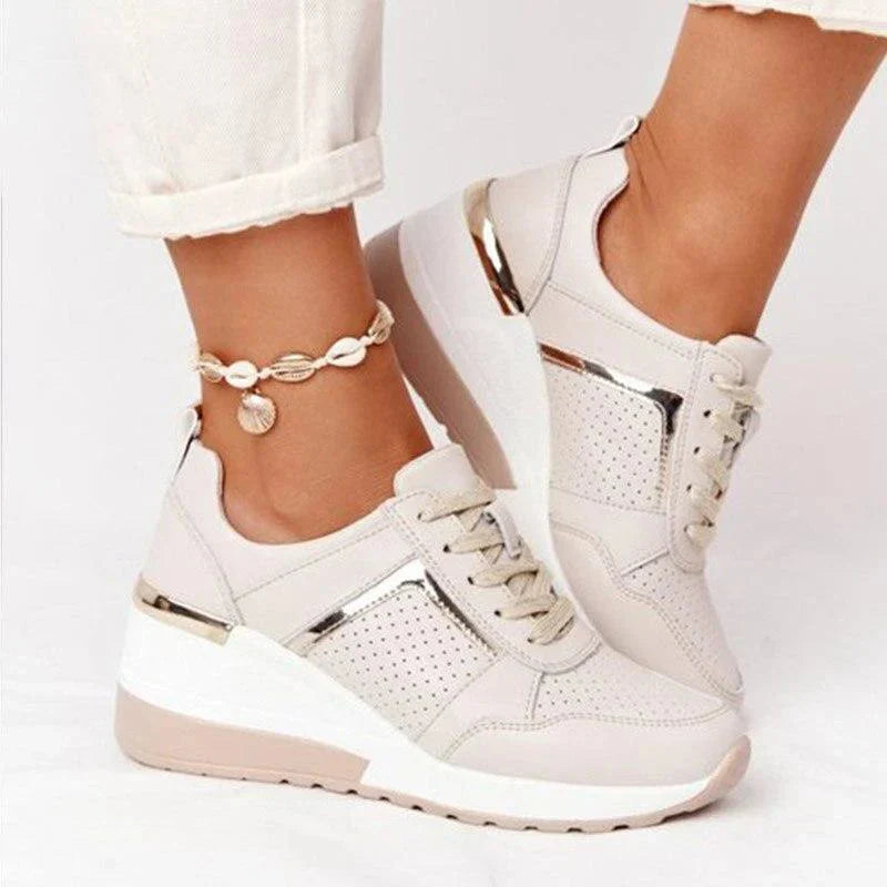 Sneakersy damskie ortopedyczne na koturnie noszone z białymi spodniami, widok z przodu na perforowaną cholewkę