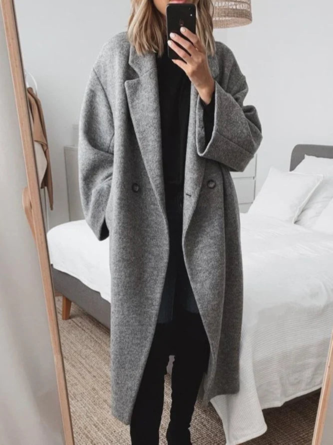 Woman wearing grey oversized wool-blend coat with double-breasted front and notched lapels over black outfit