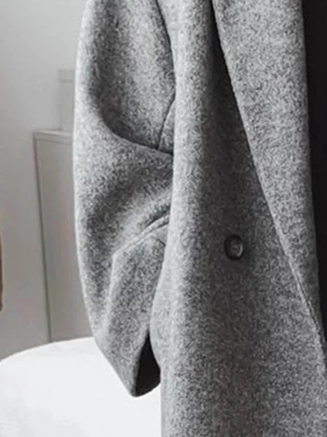 Grey longline women's coat with relaxed fit and drop shoulders styled casually indoors