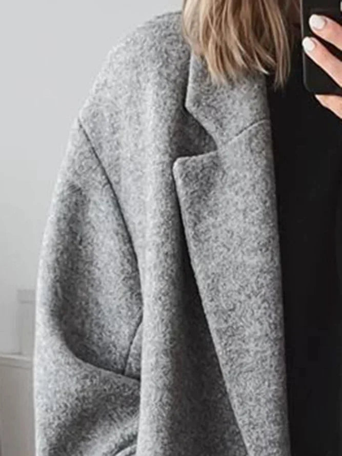Oversized women's coat in grey featuring wide lapels and below-knee length silhouette