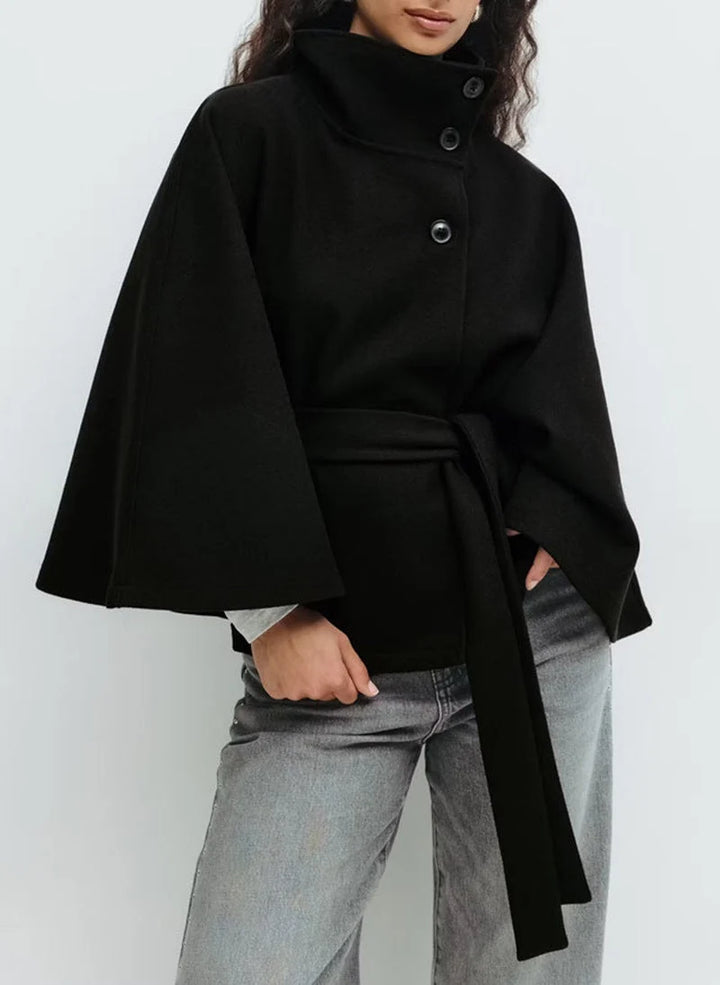Elegancka peleryna z paskiem prezentowana od tyłu z widocznym szerokim rękawem typu kimono