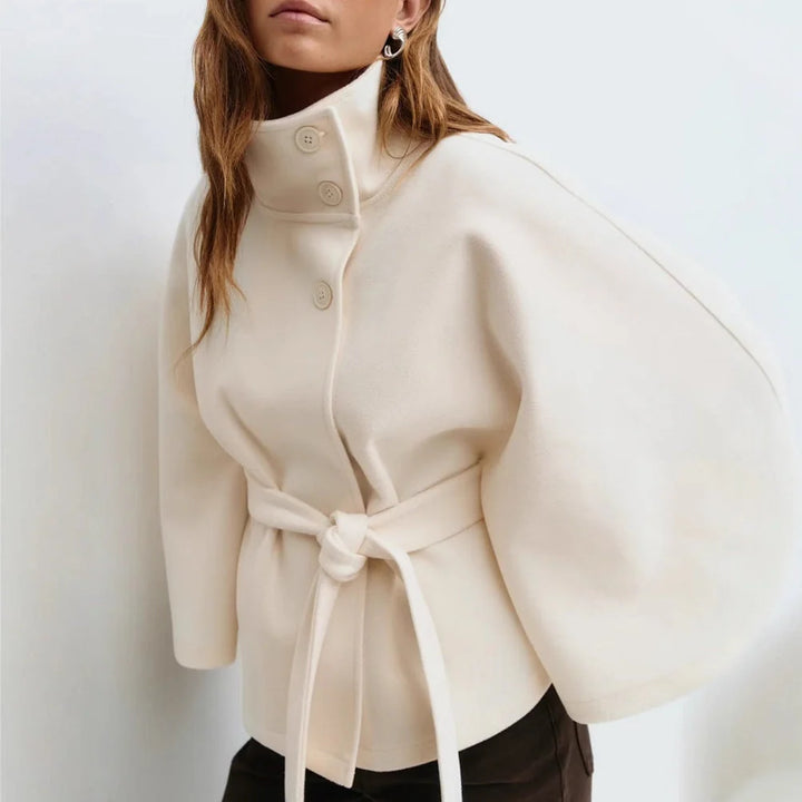 Cała sylwetka modelki w eleganckiej pelerynie z wysoką stójką i paskiem w talii