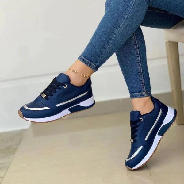 Eleganckie damskie buty sportowe w kolorze granatowym z białymi paskami i ergonomiczną podeszwą, noszone z jeansami