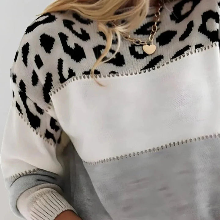 Sweter dzianinowy z wzorzystą górną częścią prezentowany w casualowej stylizacji z torebką