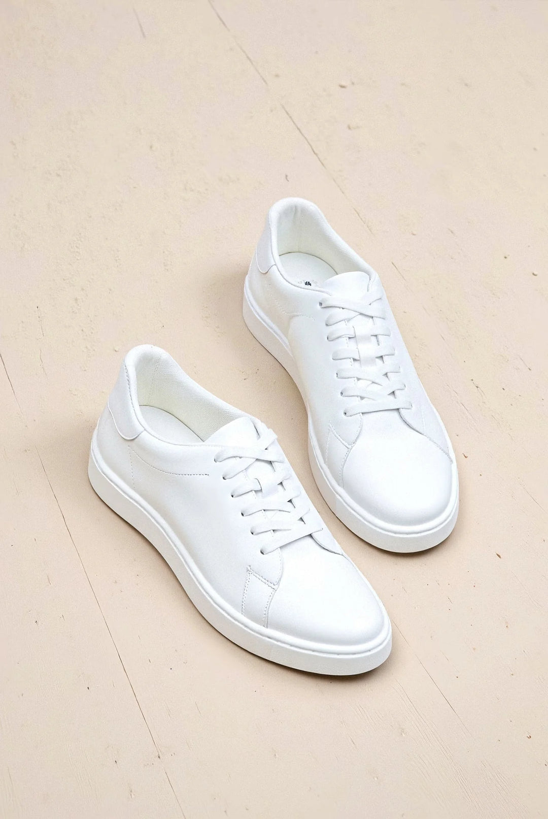 Para białych sneakersów męskich minimalistycznych z widokiem od góry prezentująca czysty design i sznurowanie