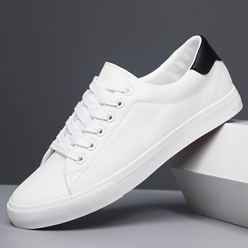 Klasyczne białe sneakersy męskie z czarnym detalem, niskie wykończenie, teksturowana podeszwa, minimalistyczny design, widok z przodu.