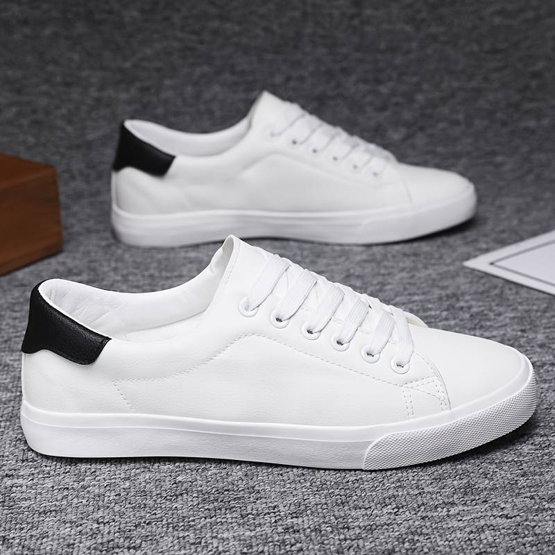 Sneakersy męskie białe z kontrastowym czarnym panelem, sznurowanie na sześć oczek, gładki materiał, widok z góry.