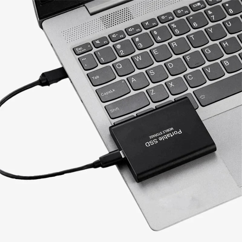 Kompaktowy dysk SSD z interfejsem USB Type-C leżący na laptopie obok klawiatury