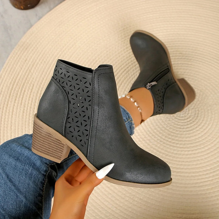 Close-up of women's ankle boots showing side zip fastening and geometric laser-cut pattern