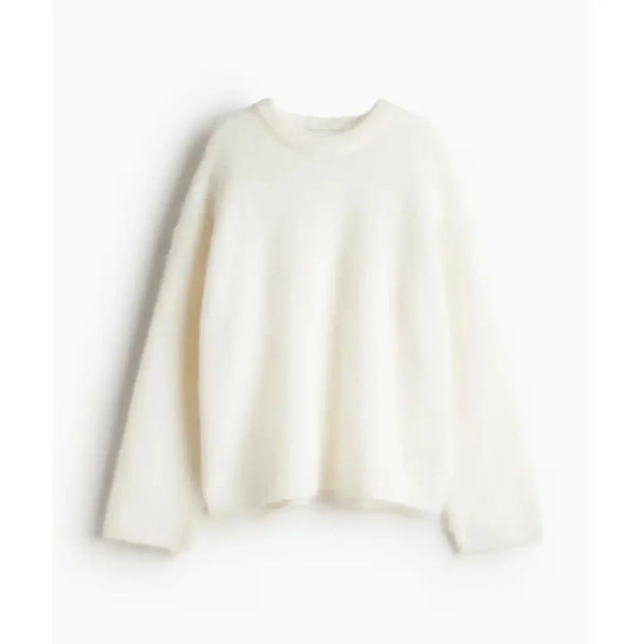 Sweter damski oversize w kremowym kolorze z okrągłym dekoltem i długimi rękawami na białym tle
