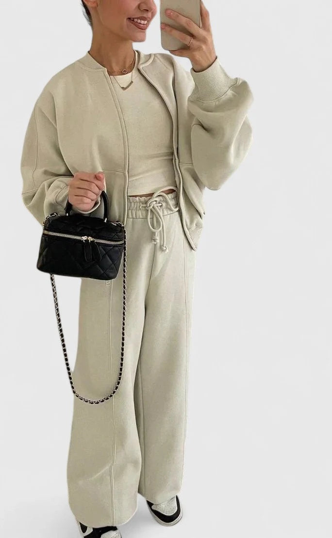 Kobieta w szarym zestawie dresowym z czapką, trzymająca torbę, casualowy look