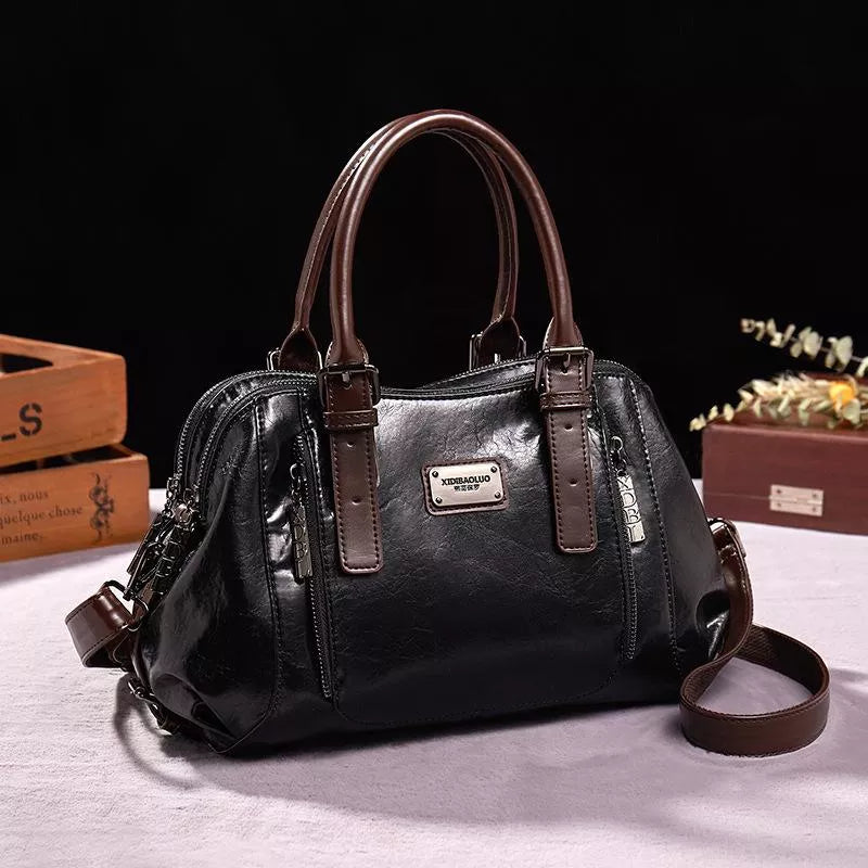 Brązowa elegancka skórzana torba damska z bocznymi suwakami i metalową plakietką marki